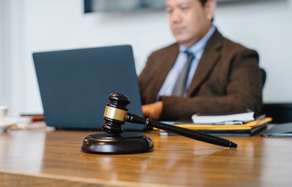 lawyer typing at computer, gavel on desk beside him