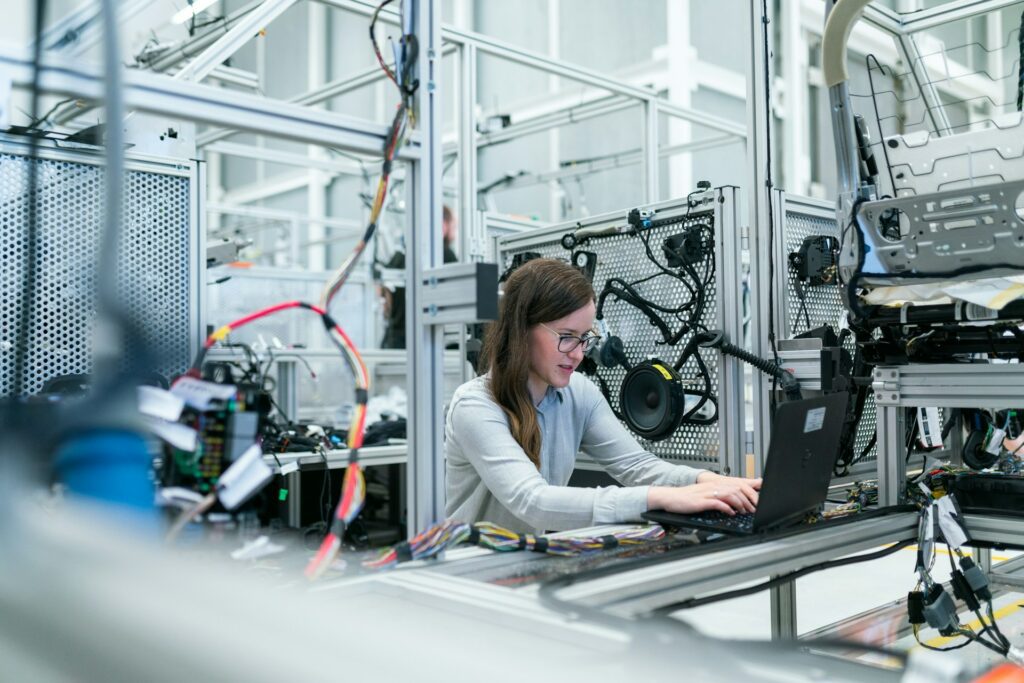 woman typing on computer in manufacturing warehouse