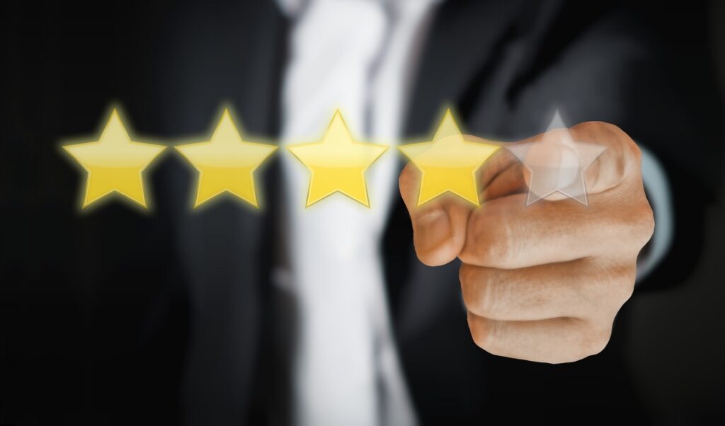 A person with 5 stars in front of him, with 4 stars filled in and the person pointing reaching for the 5th star for their business review.