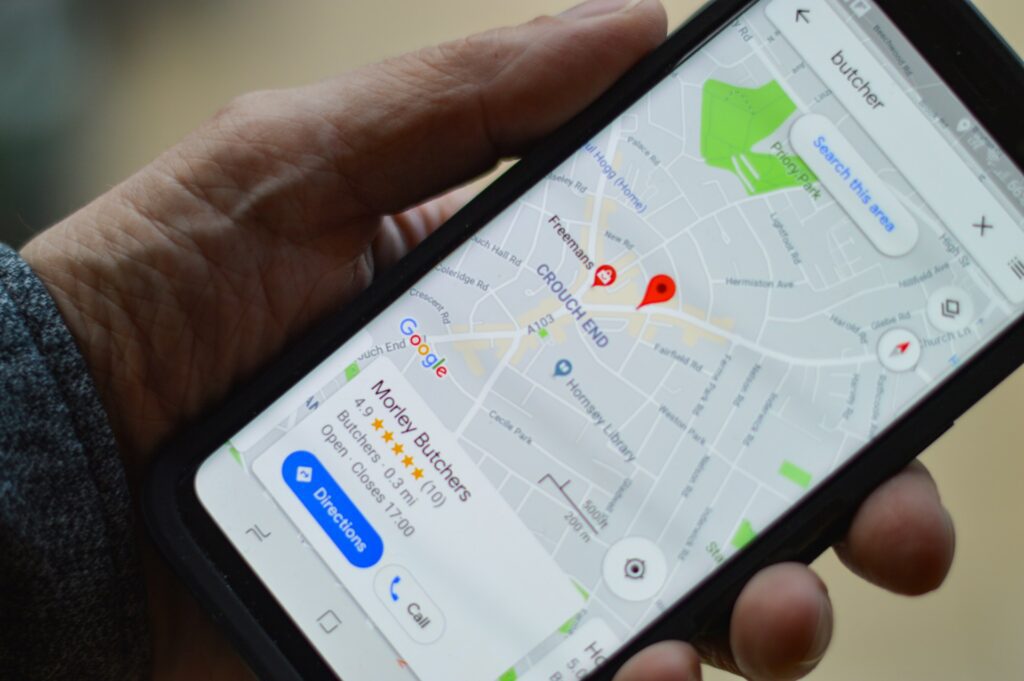 Someone's hand is holding a phone with a map on it locating a specific business.