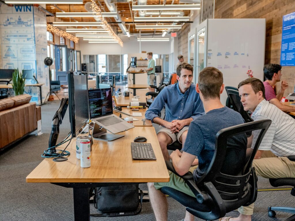 several people are sitting at a table with computers talking
