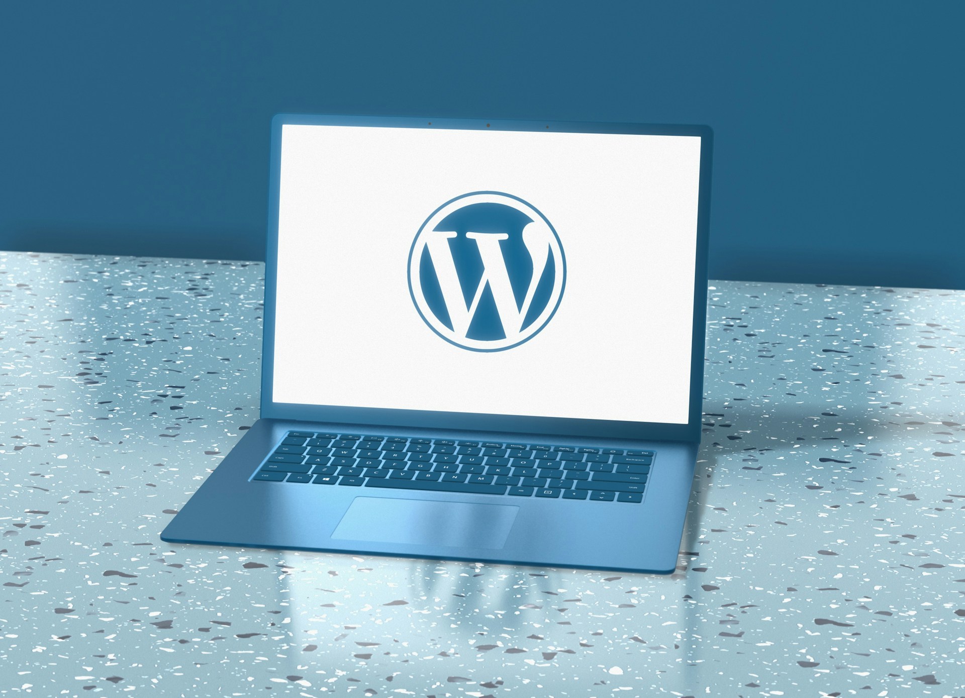 A laptop with the WordPress logo is sitting on a counter